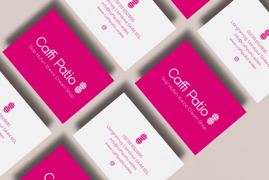 A flatlay of multiple business cards designed using Caffi Patio's new logo design and the vibrant pink