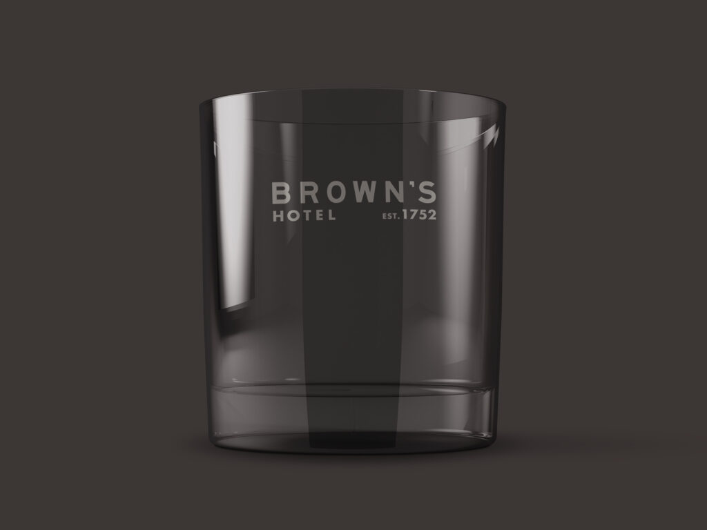 A smoky translucent whiskey glass with the Brown's Hotel logo on the glass