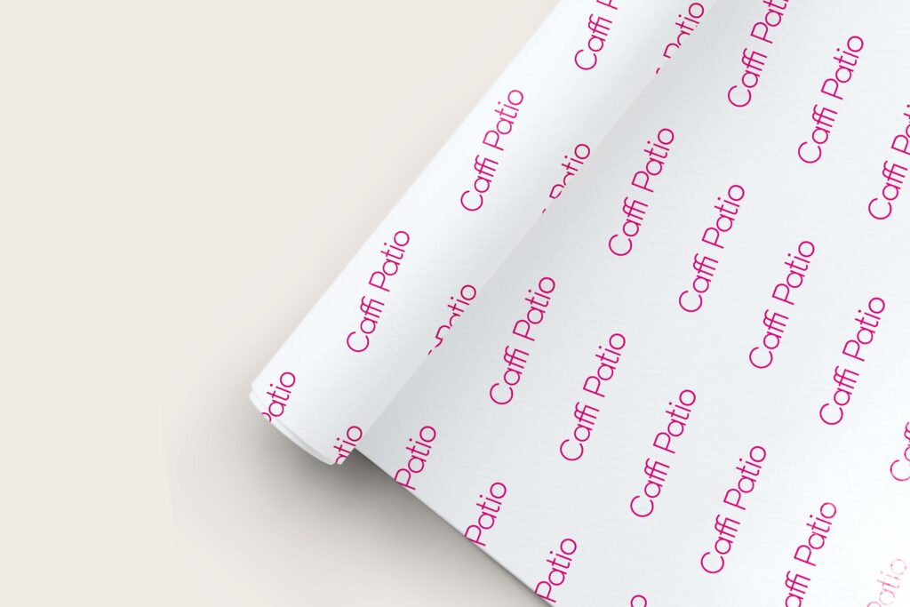 A roll of white paper with Caffi Patio's new logo in vibrant pink repeated across the roll