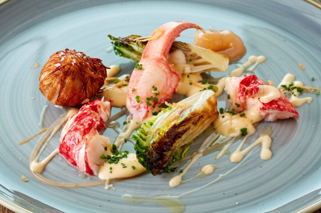 A blue plate with a lobster dish on it from the high-end restaurant Beach House