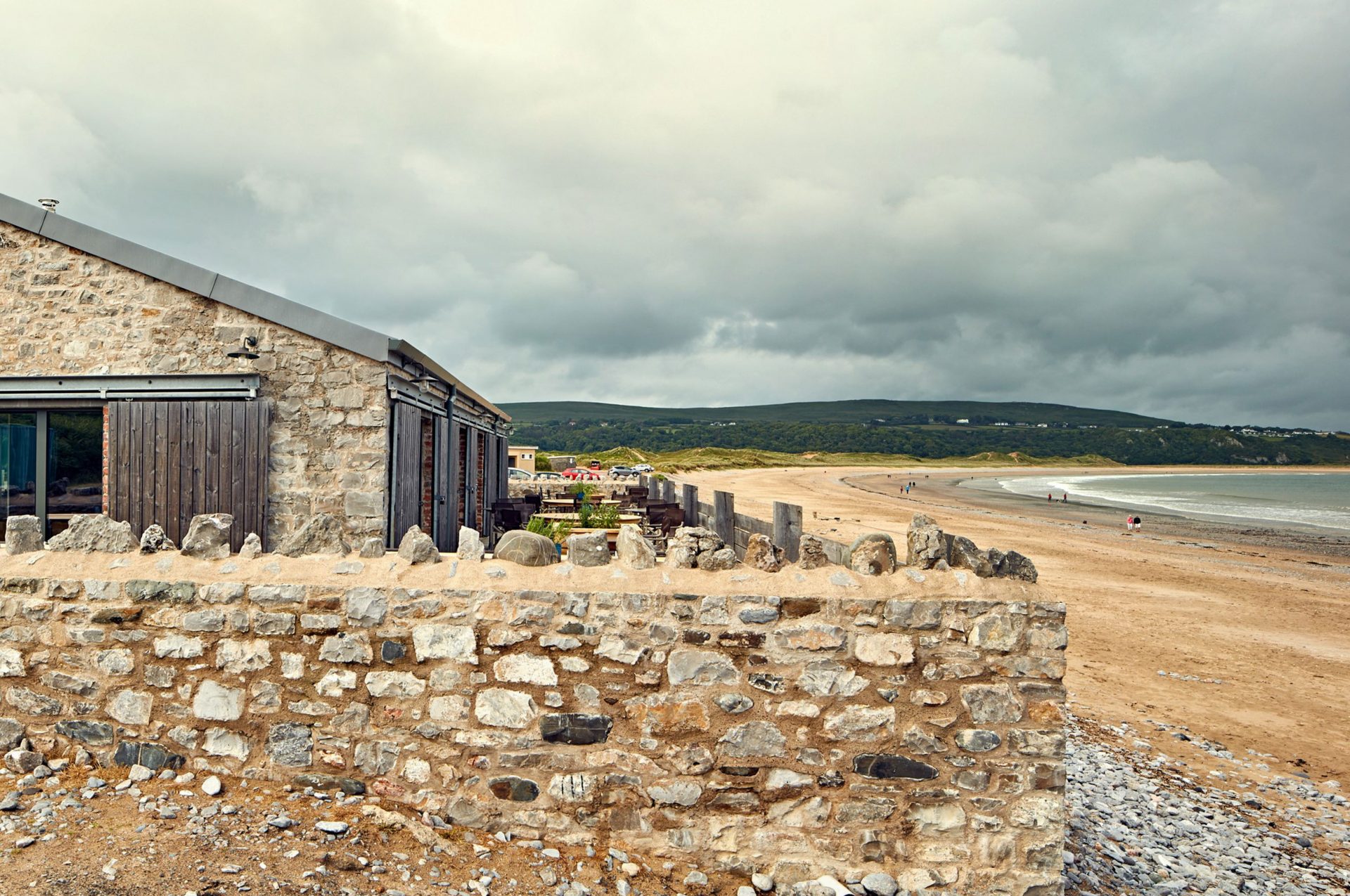 A view of the Gower, a golden sandy beach, with Beach House's exterior in the foreground