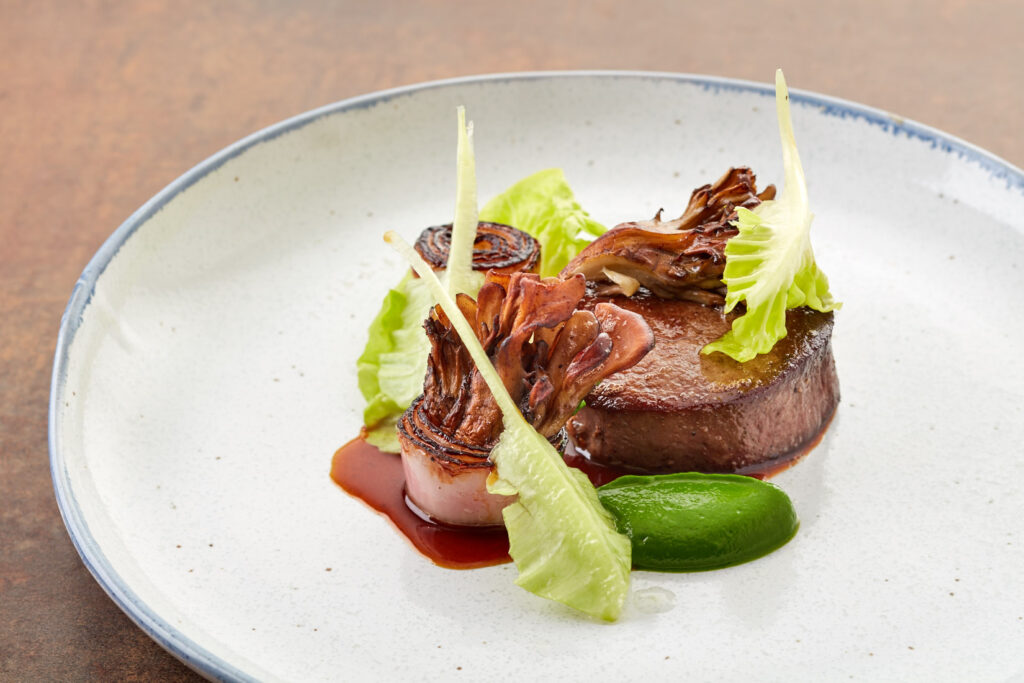 An off-white plate with a blue edge with a meat and vegetable dish on it
