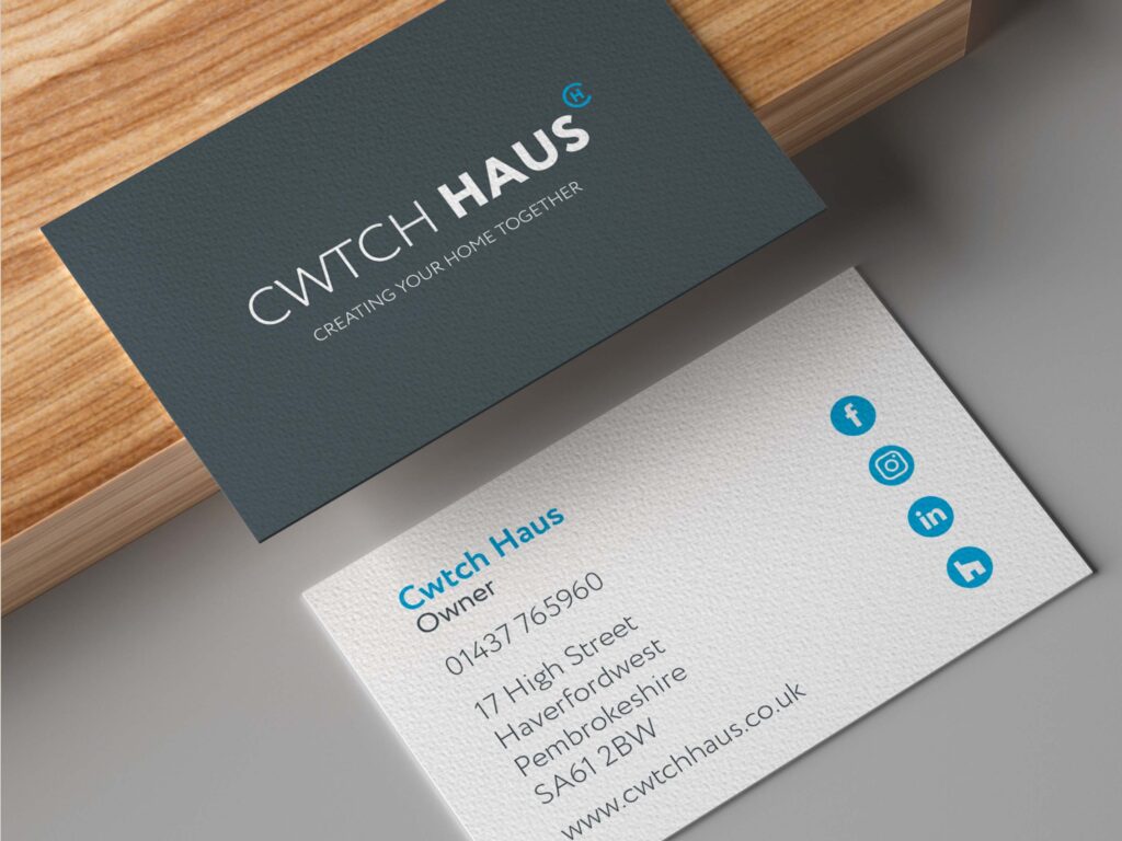 Front and back of a business card; the front is dark grey with the Cwtch Haus logo, and the back is white with blue and grey details