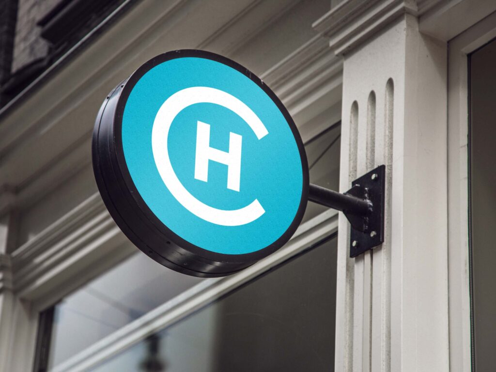 A round sign outside of a storefront with a vibrant blue colour and a H inside of a large C