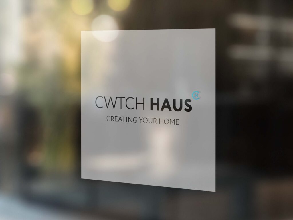 A window with a white vinyl sticker with the Cwtch Haus logo