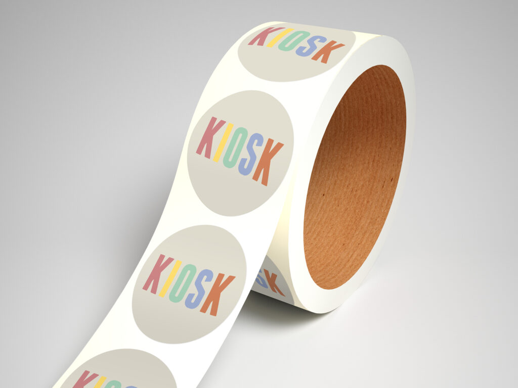 A roll of round off-white stickers with KIOSK written on the center in its vibrant logo