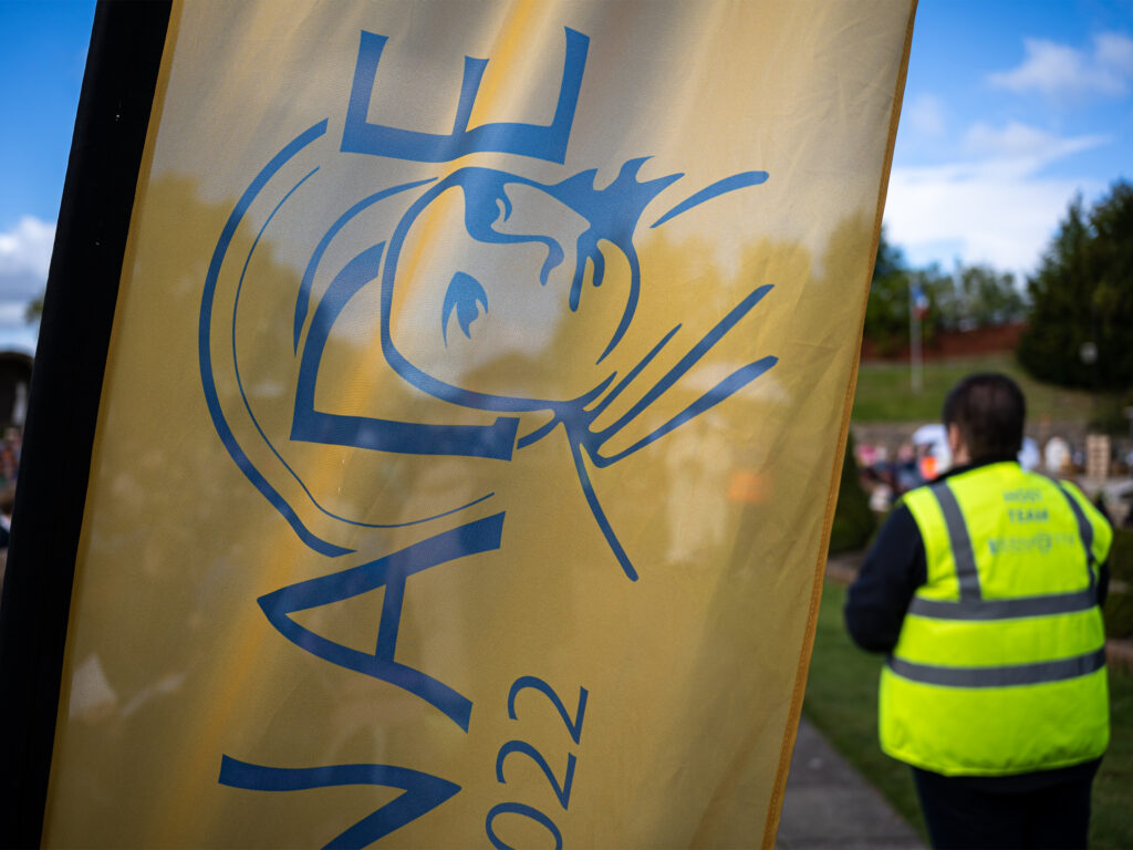 A close up of a yellow flag with the Saint Bernadette Relic Tour 2022 logo in blue