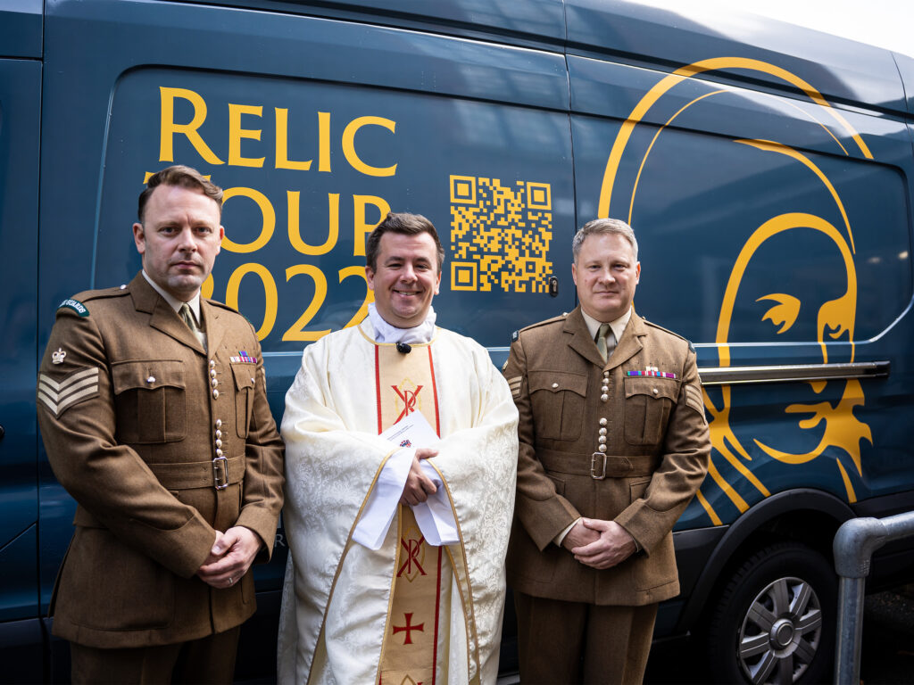 Three people stood in front of a blue van with yellow text saying 'RELIC TOUR 2022'