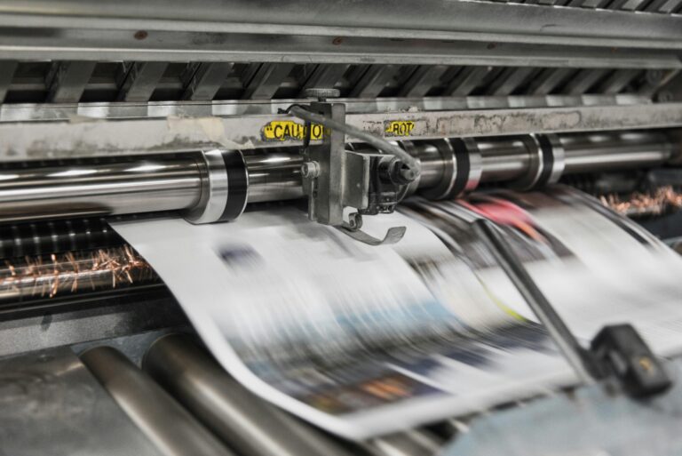 A close up of a professional printer with printed sheets quickly coming out of the printer